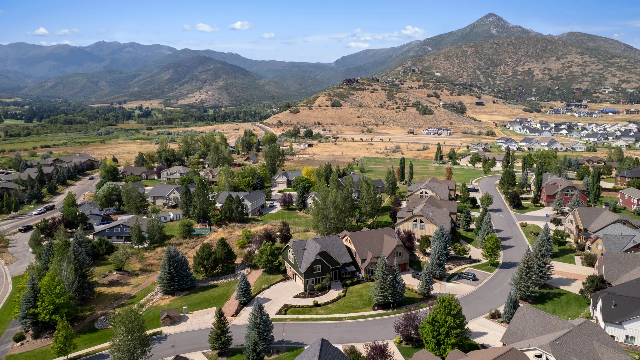 Expansive residential area with mature landscaping, curvilinear streets, and a mountainous backdrop