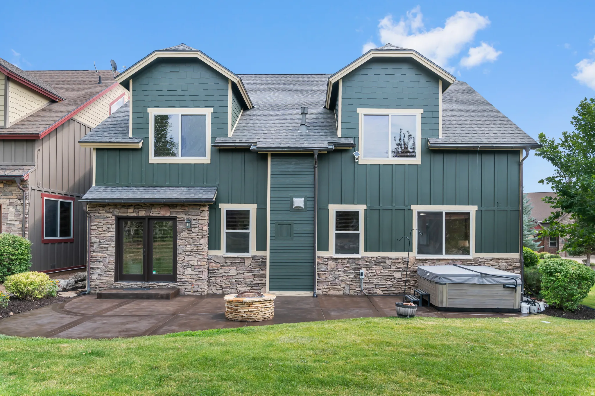 Spacious backyard featuring a stone patio, built-in fire pit, and a hot tub