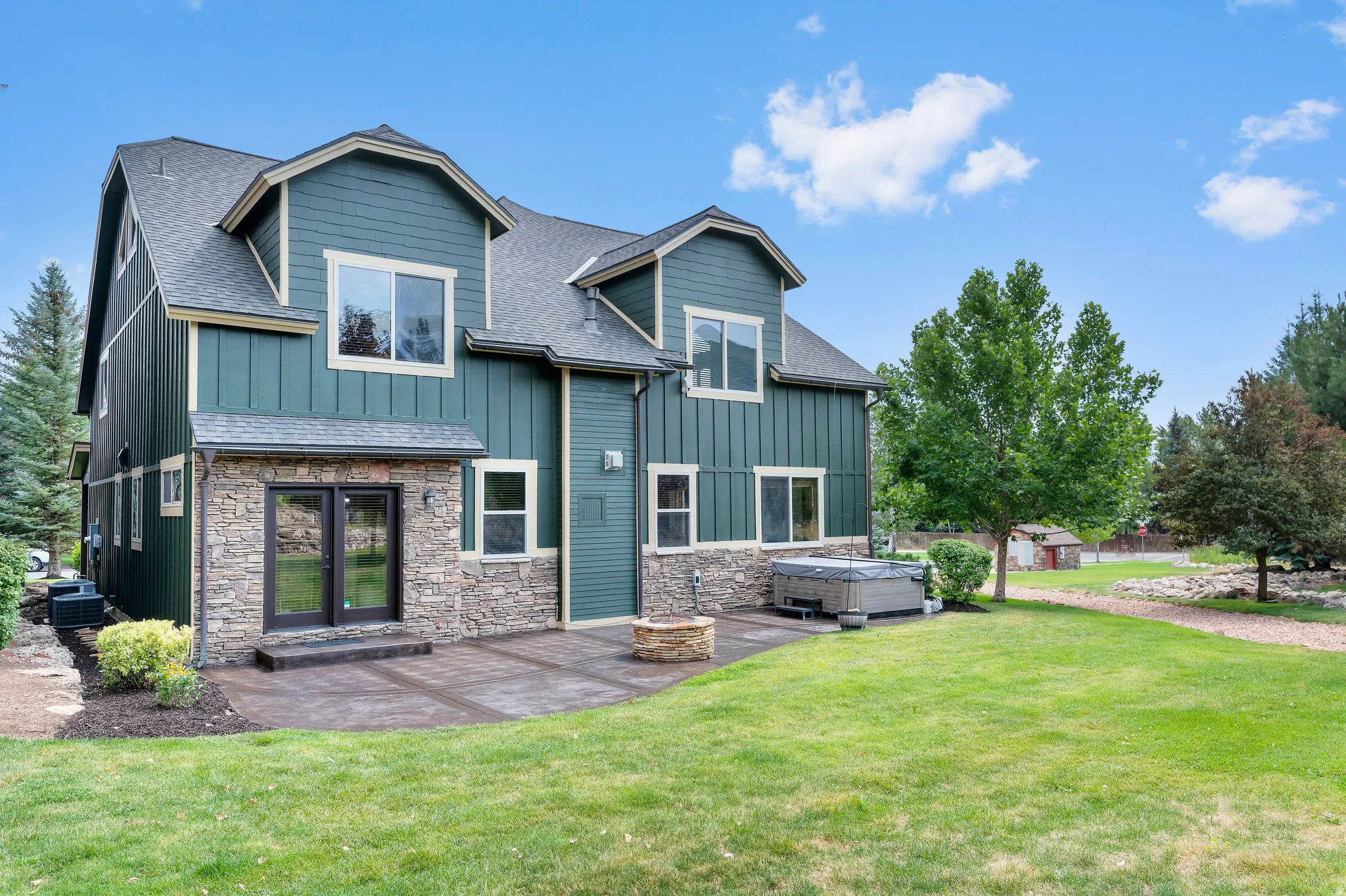 Board and batten siding, stone facade, paved patio, dual pane windows, and a built-in fire pit