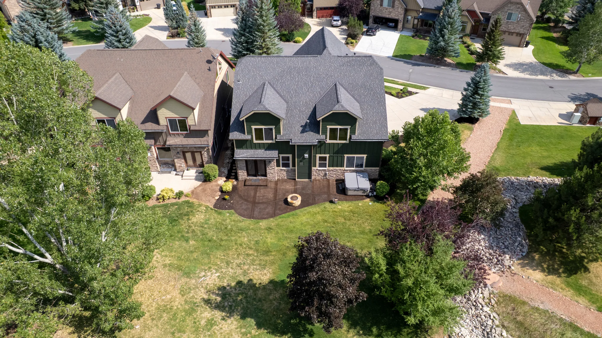 Expansive backyard featuring a stone patio, fire pit, and built-in spa
