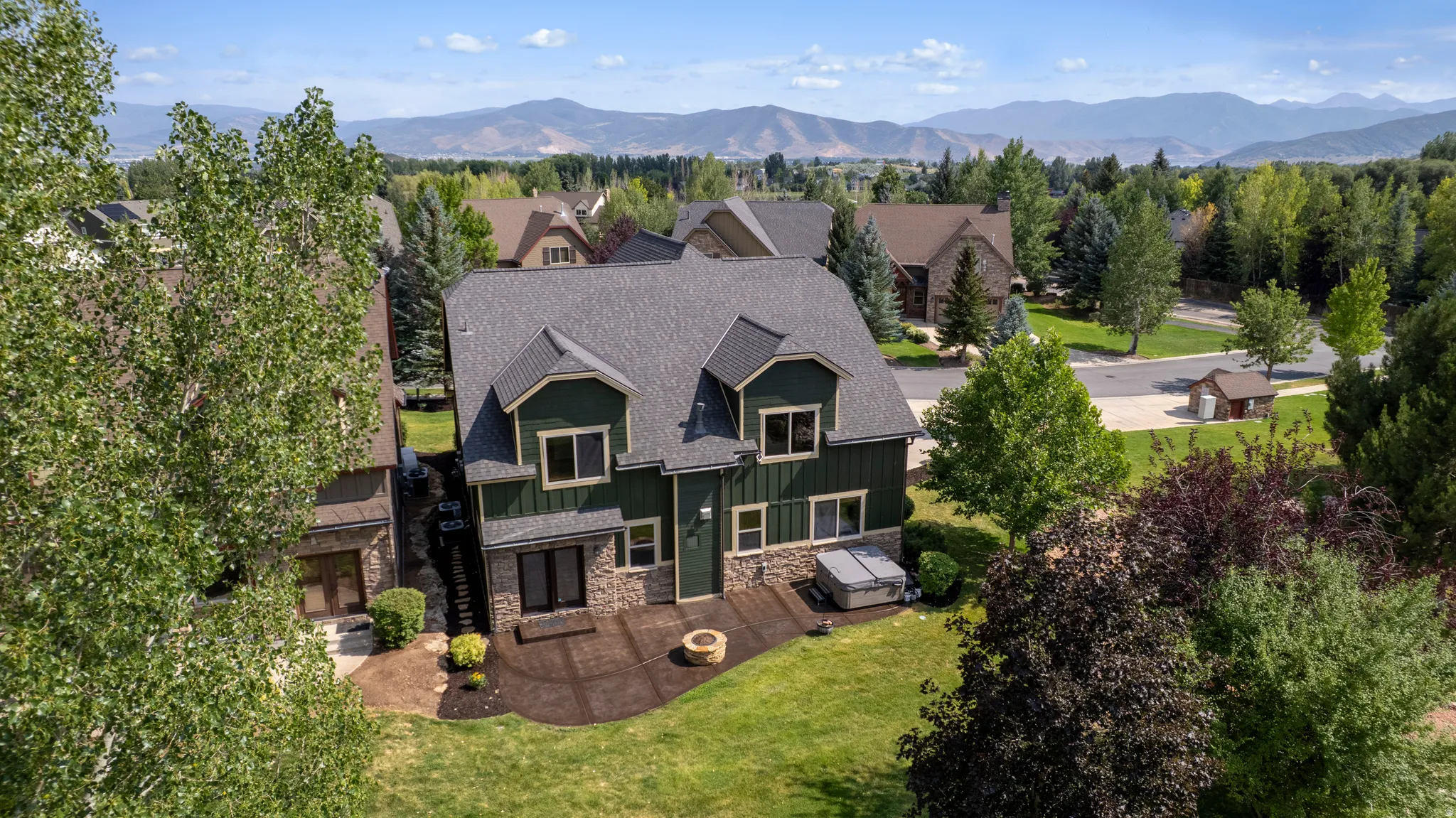 Two-story residence featuring a dark green facade with stone accents