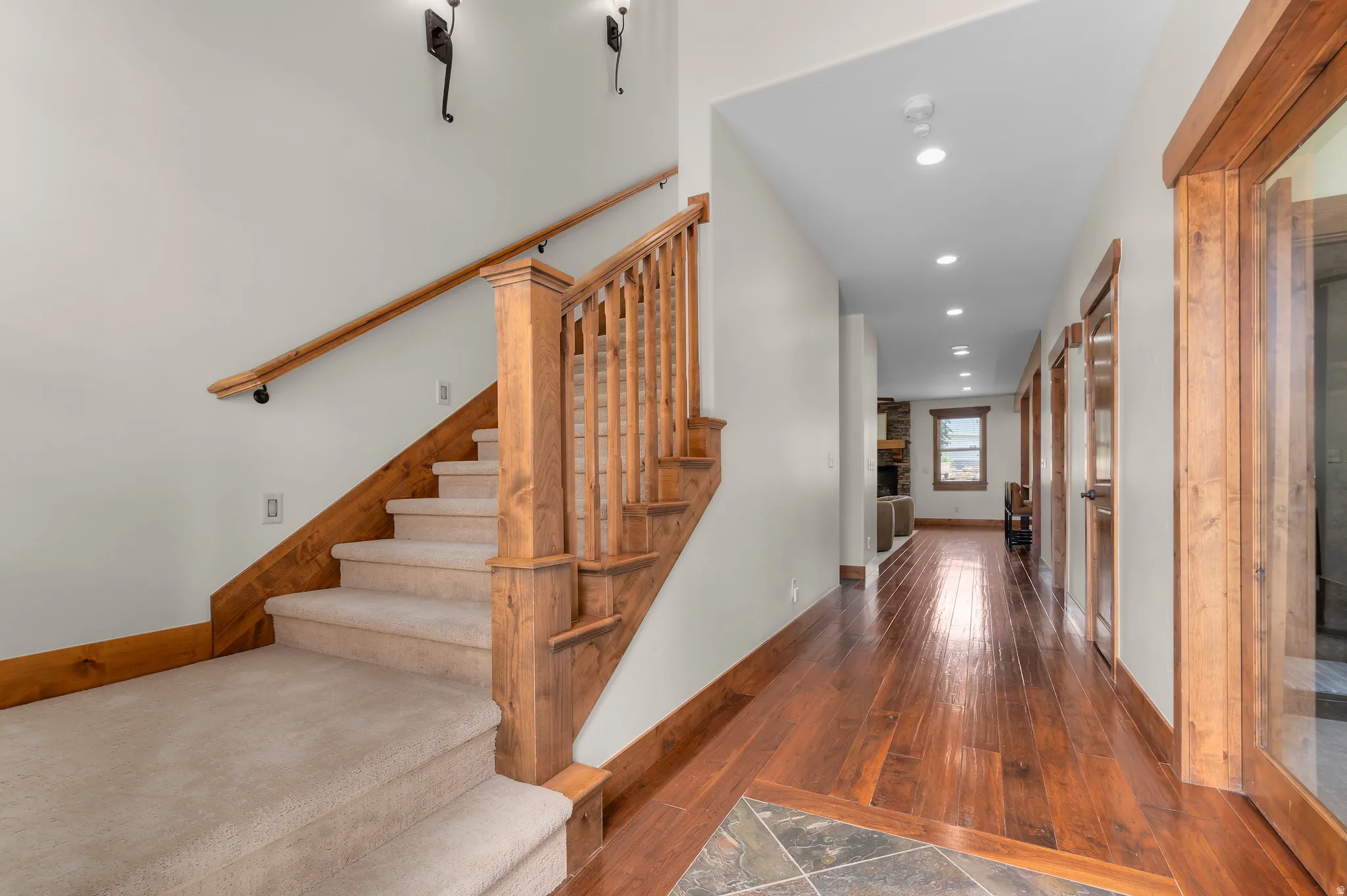 Hardwood flooring, wood-finish trim, recessed lighting, and carpeted stairs with wood-finish railing