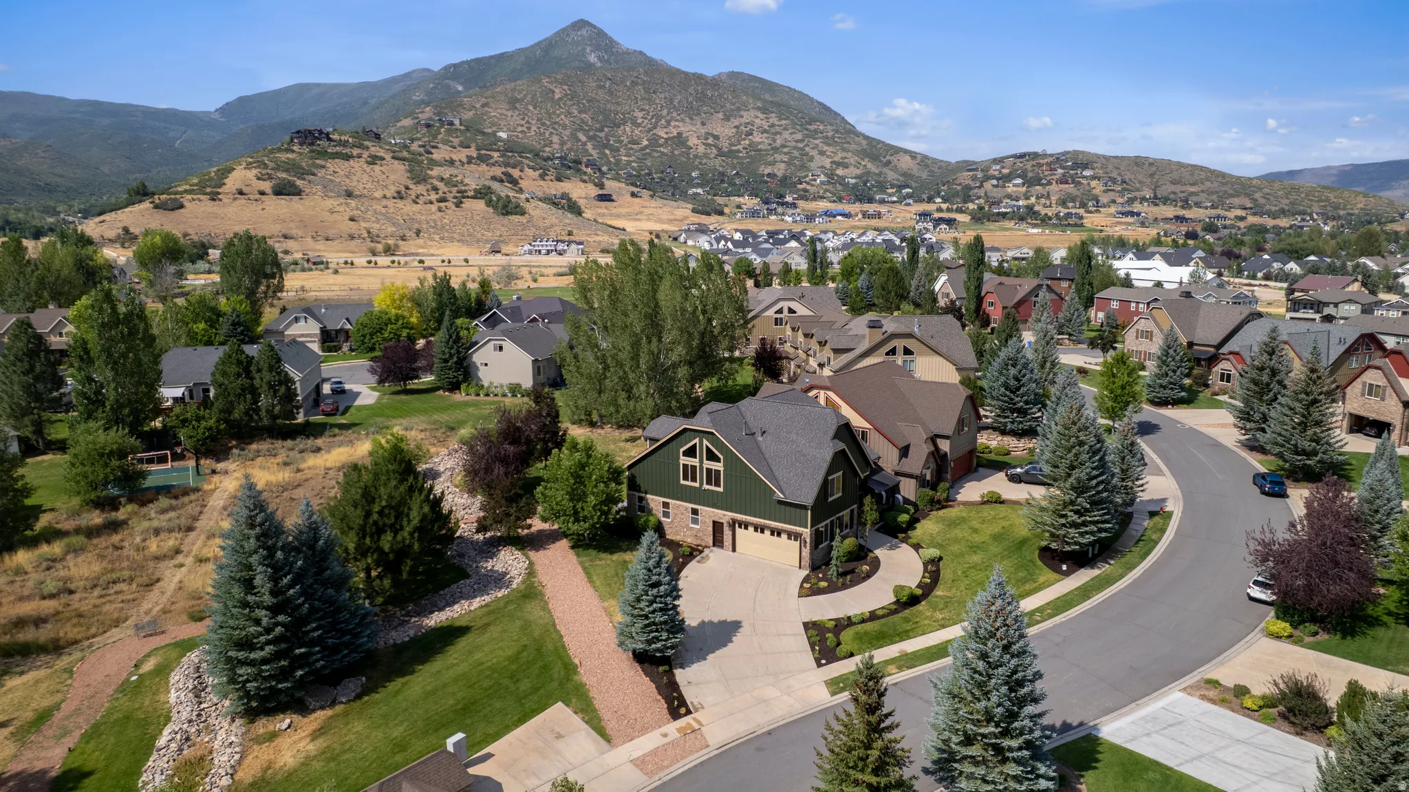 Mature landscaping with established trees, paved driveway leading to an attached garage, and a cul-de-sac street