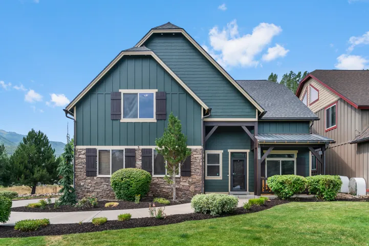 Contemporary two-story residence featuring a striking gable roofline with mixed exterior finishes including board-and-batten siding and stone veneer detailing