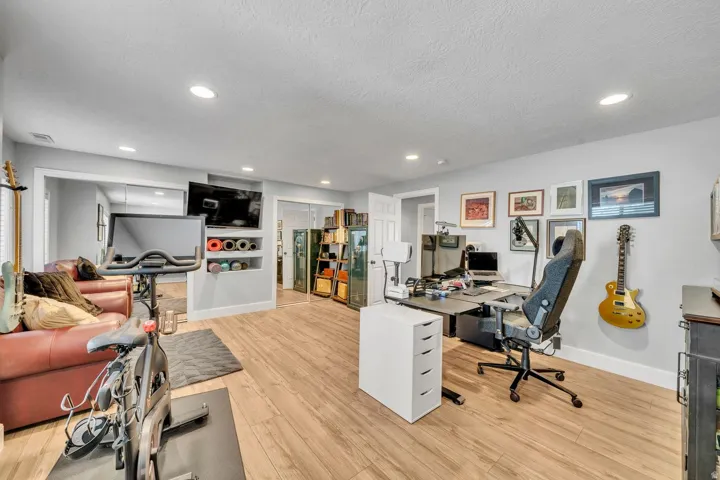 Recessed lighting, wood-finish flooring, built-in shelving, white trim, and a white door