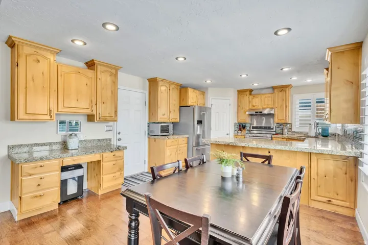Recessed lighting illuminating a kitchen featuring wood cabinetry, stainless steel appliances, and a tiled backsplash