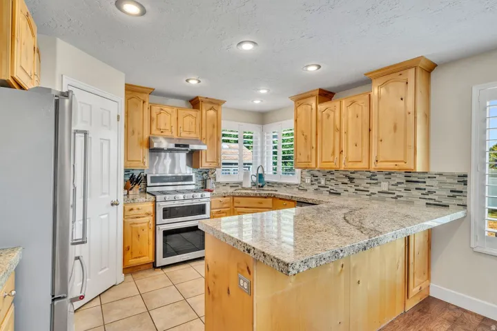 Kitchen featuring wood cabinetry, light-toned countertops, a mosaic tile backsplash, recessed lighting, and tile flooring