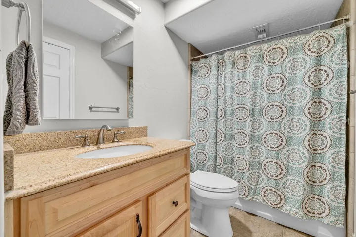 Vanity with a granite countertop and an undermount sink, brushed nickel faucet, and wood-finish cabinetry