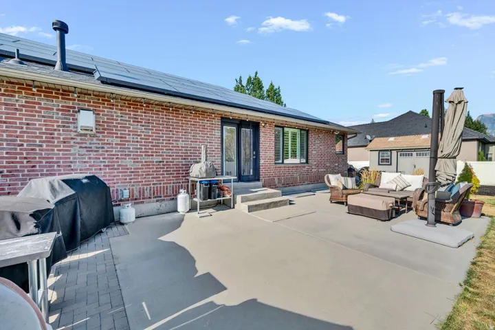 Brick exterior featuring solar panels, concrete patio, and a double glass door entry