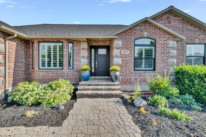 Brick exterior with stone accents, dark-framed windows, and decorative shutters