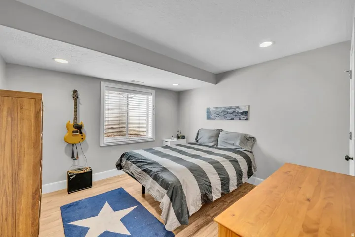 Recessed lighting illuminating the room, wood-finish flooring, a window with blinds, and white trim