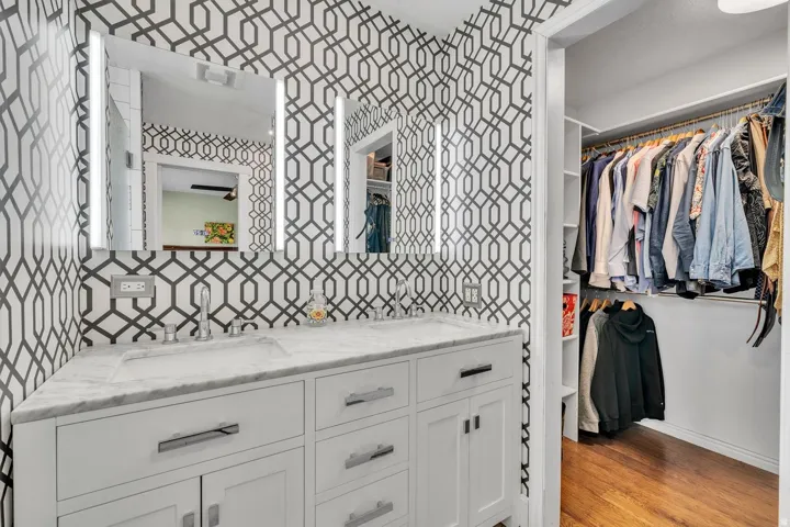 Dual vanity with integrated sinks, illuminated mirrors, and a built-in closet with shelving
