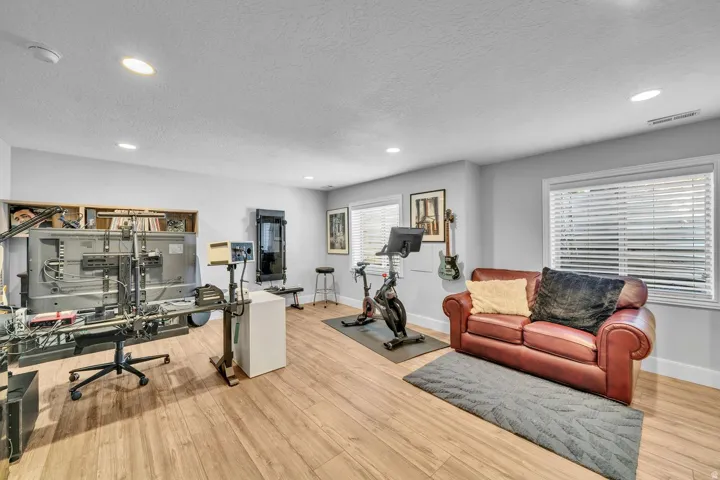Recessed lighting, light gray wall color, wood-finish flooring, built-in shelving, and multiple windows with blinds