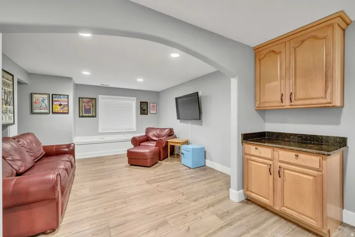 Spacious room with wood-finish flooring, recessed lighting, and an arched entryway