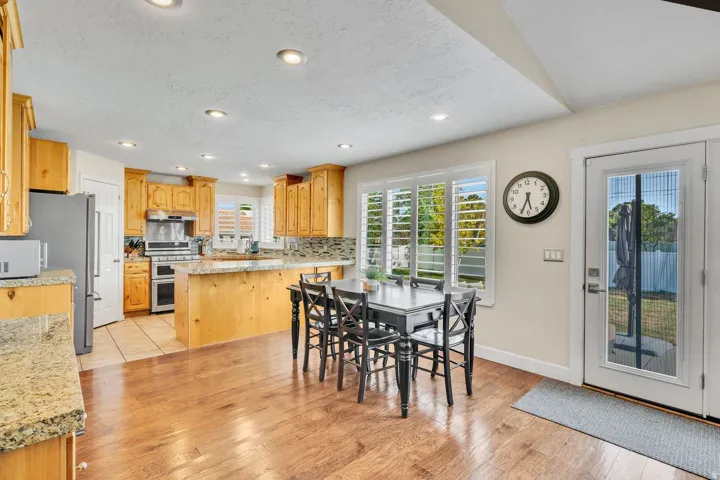 Hardwood-finish flooring, recessed ceiling lights, wood cabinetry, stone countertops, and a full-light patio door