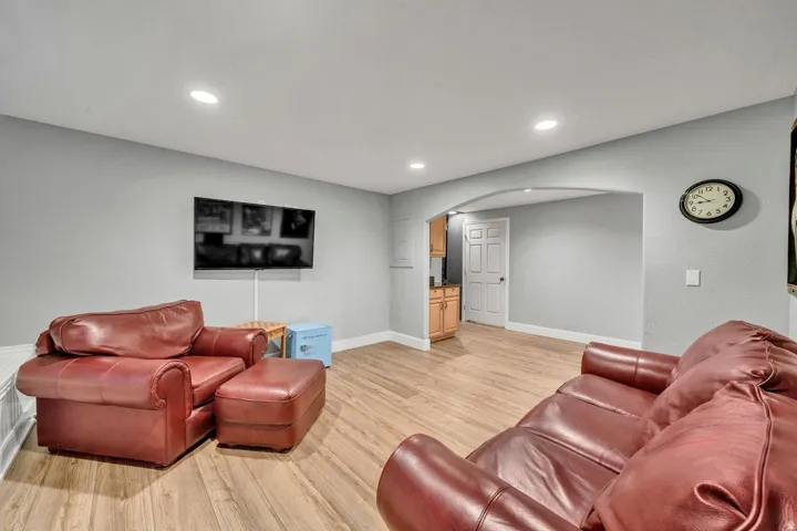 Recessed lighting illuminating wood-finish flooring, an arched doorway, and built-in cabinetry with a countertop