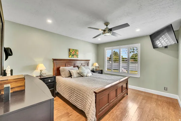 Hardwood-style flooring, recessed lighting, ceiling fan, window with white plantation shutters, and painted walls
