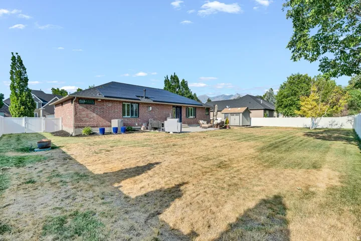 Brick exterior with dark roof, white privacy fencing, and a concrete patio