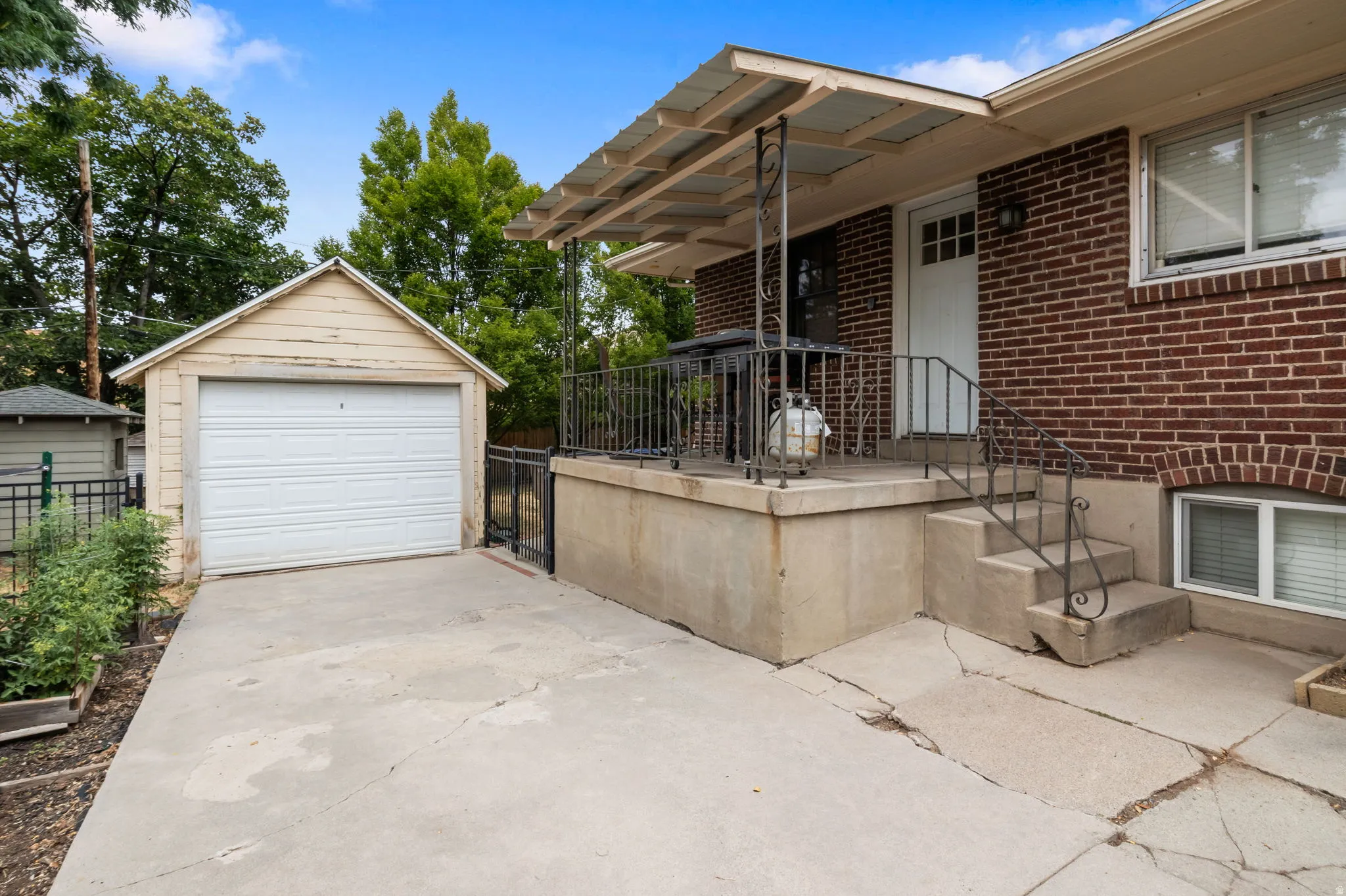 Brick exterior with a covered porch featuring wrought iron railings