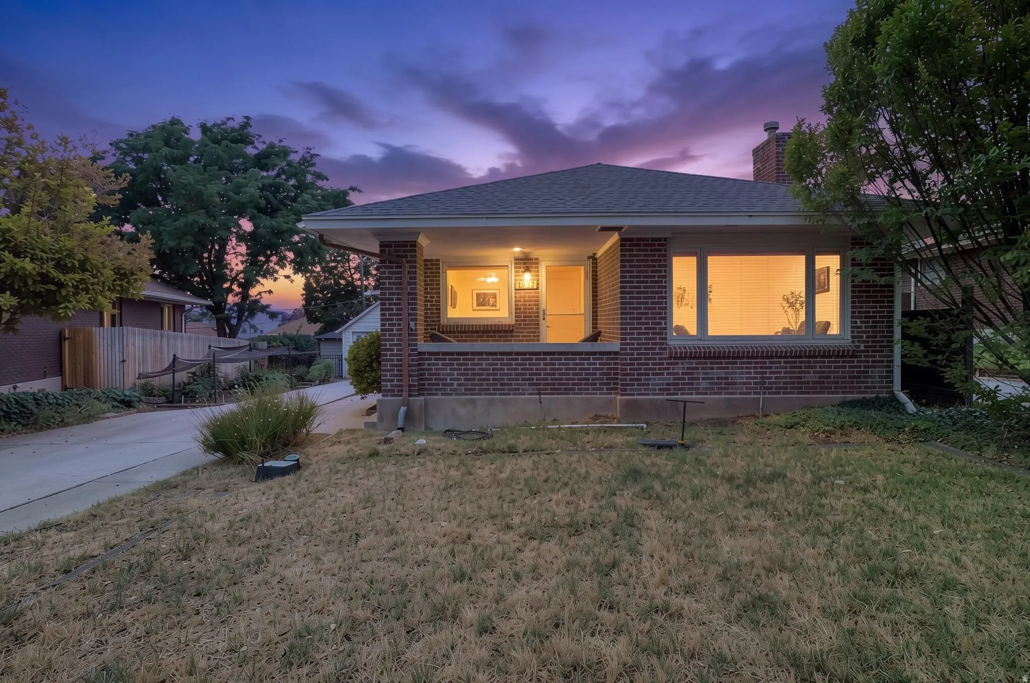 Brick exterior with a covered porch, multiple windows, and a dark shingled roof
