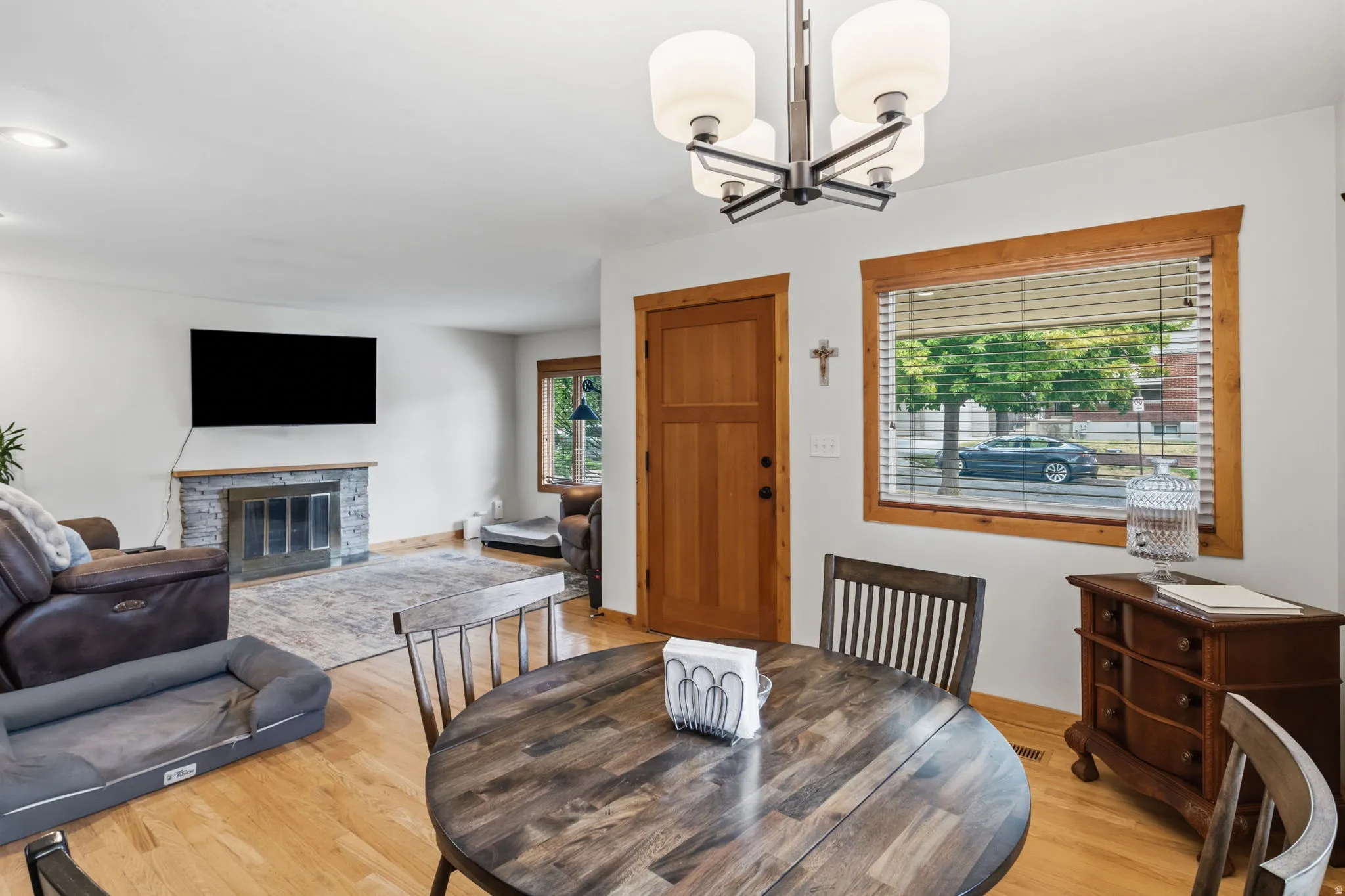 Hardwood flooring, stone-clad fireplace, recessed lighting, and a multi-light ceiling fixture