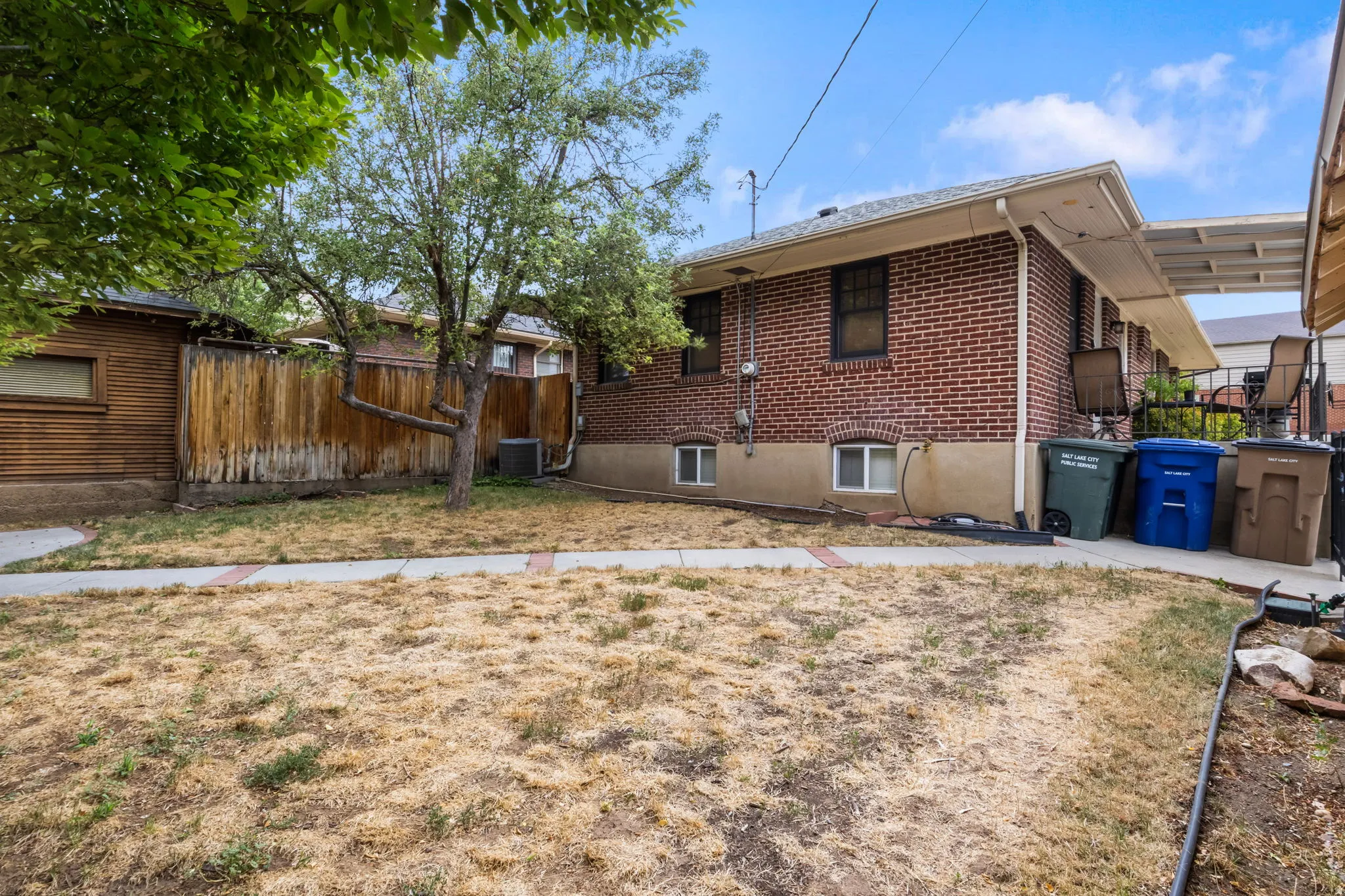 Brick exterior, mature trees, wood fencing, covered patio, paved walkway