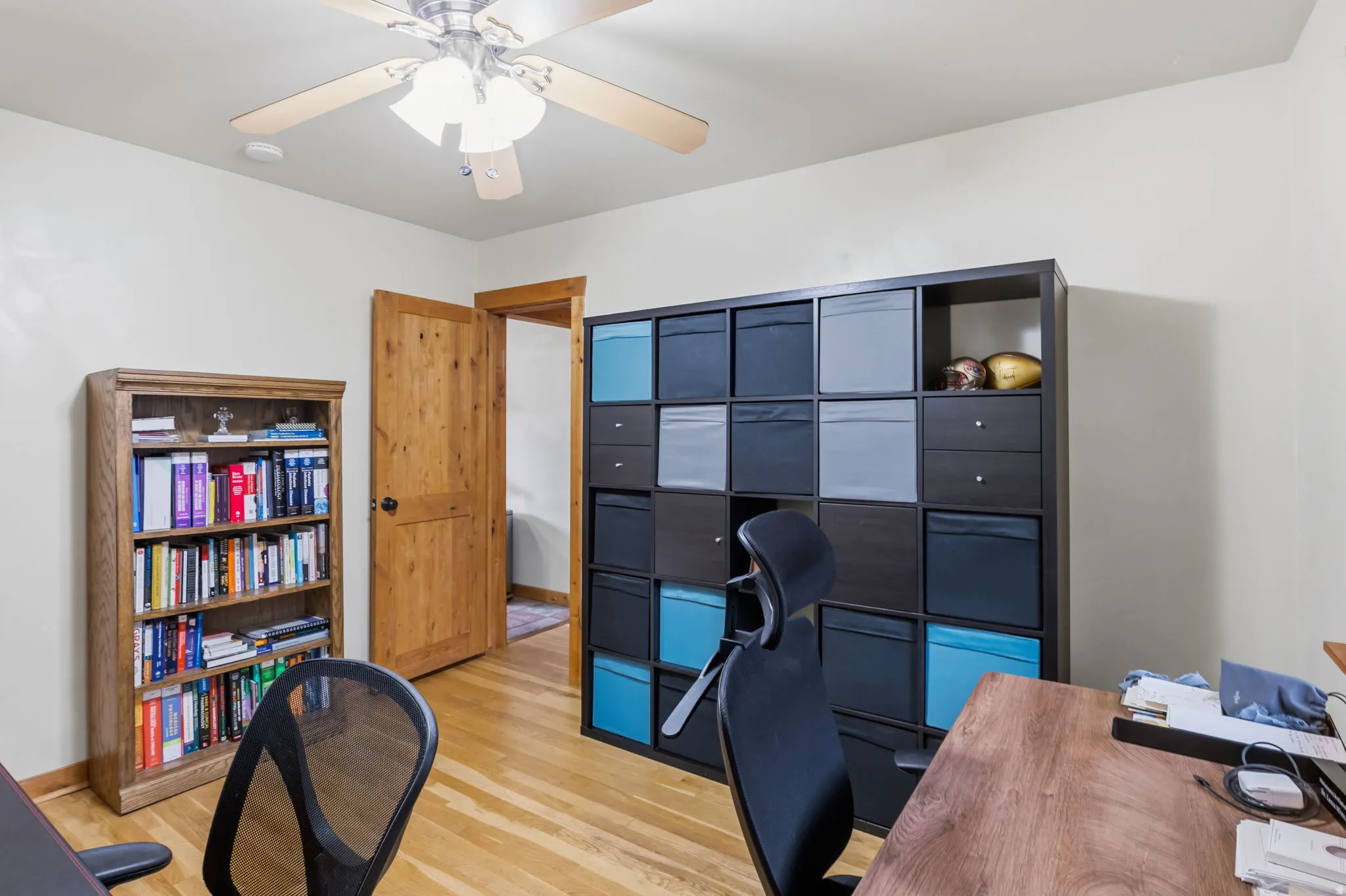 Light wood-finish flooring with a ceiling fan light fixture