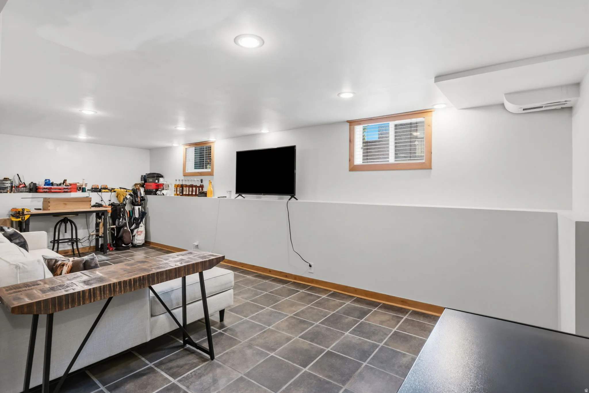 Recessed ceiling lighting, tiled flooring, wood-framed windows with blinds, and a wall-mounted mini-split system