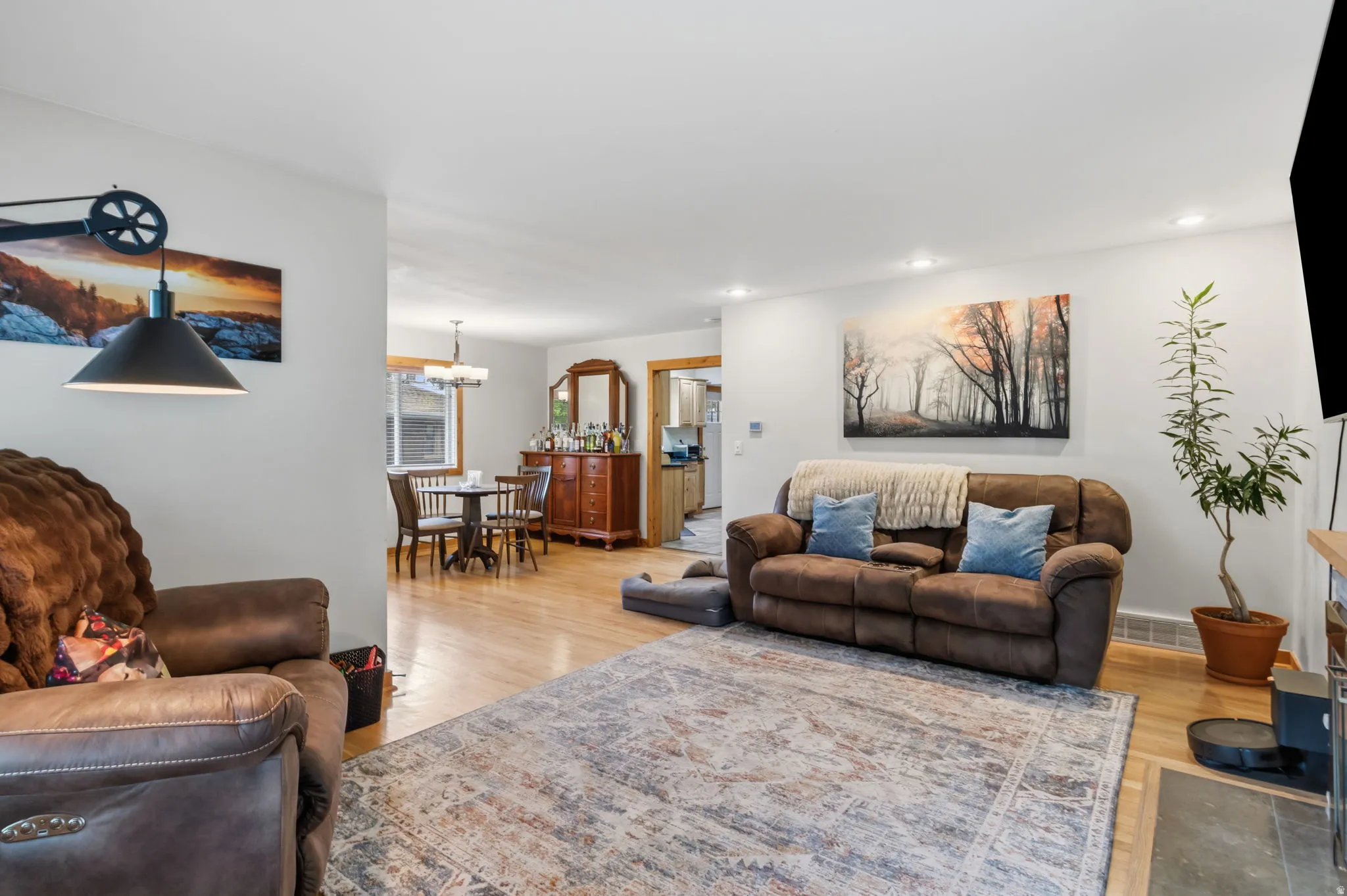 Open-concept living space featuring wood-finish flooring, recessed lighting, and a dining area with a chandelier