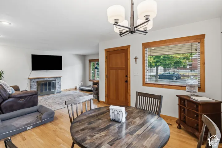 Hardwood flooring, stone-clad fireplace, recessed lighting, and a multi-light ceiling fixture