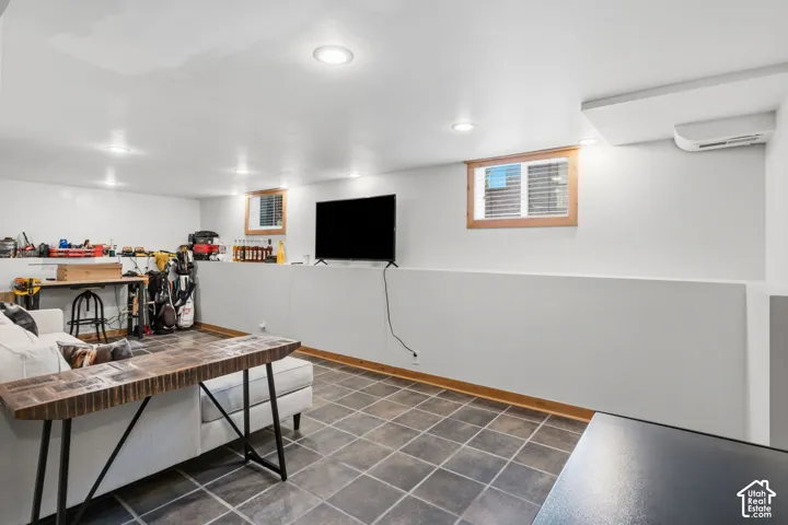 Recessed ceiling lighting, tiled flooring, wood-framed windows with blinds, and a wall-mounted mini-split system