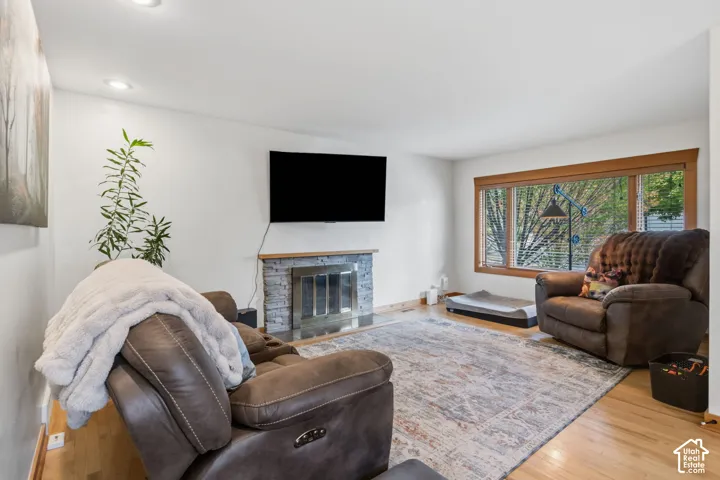 Recessed lighting, wood-finish flooring, and a stone-clad fireplace with a hearth