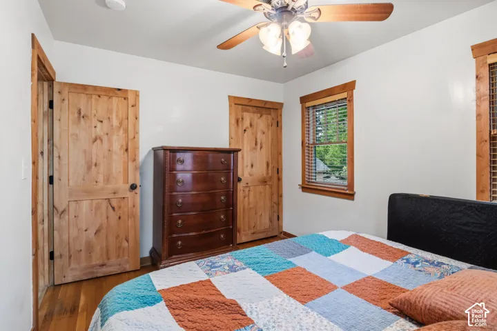 Wood-finish flooring, natural wood doors and trim, ceiling fan with light fixture, and window with blinds