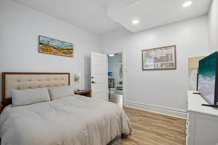 Recessed ceiling lighting, wood-finish flooring, white trim, and a white interior door