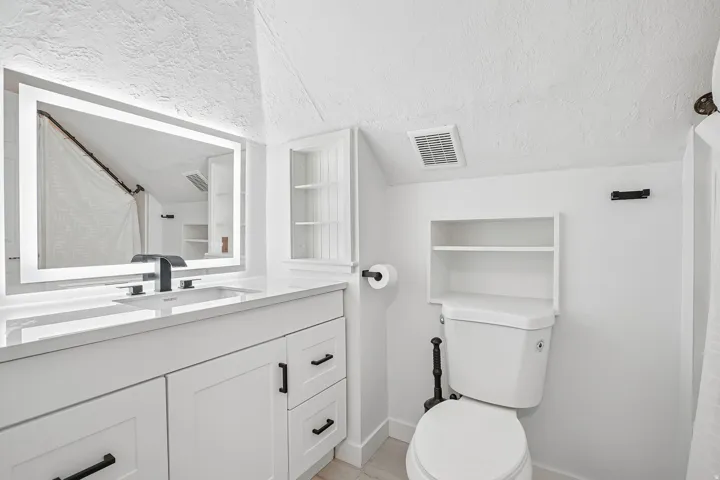 Vanity with white cabinetry, matte black hardware, and an integrated sink with a matte black faucet
