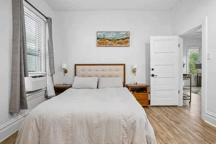 Wood-finish flooring, white paneled interior door with matte black hardware, and an accent wall sconce