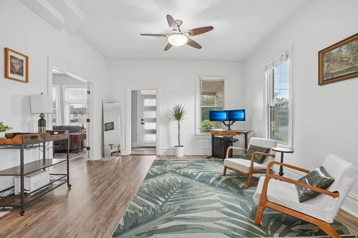 Wood-finish flooring throughout, bright white walls, and a ceiling fan with integrated lighting