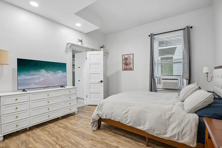 Recessed ceiling lighting, wood-finish flooring, paneled closet doors, and window with blinds