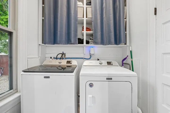 Dedicated laundry area featuring a washer and dryer, an operational window, and built-in shelving