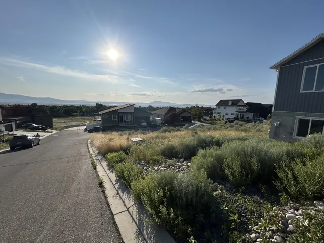 Expansive residential lot with established landscaping, paved street frontage, and mountain scenery
