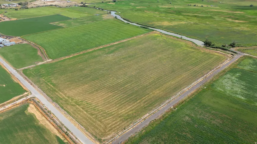 Expansive agricultural land featuring cultivated fields, a visible irrigation canal, and established perimeter roads