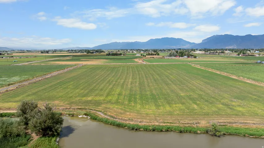 Expansive agricultural land featuring a water body and distant mountain ranges