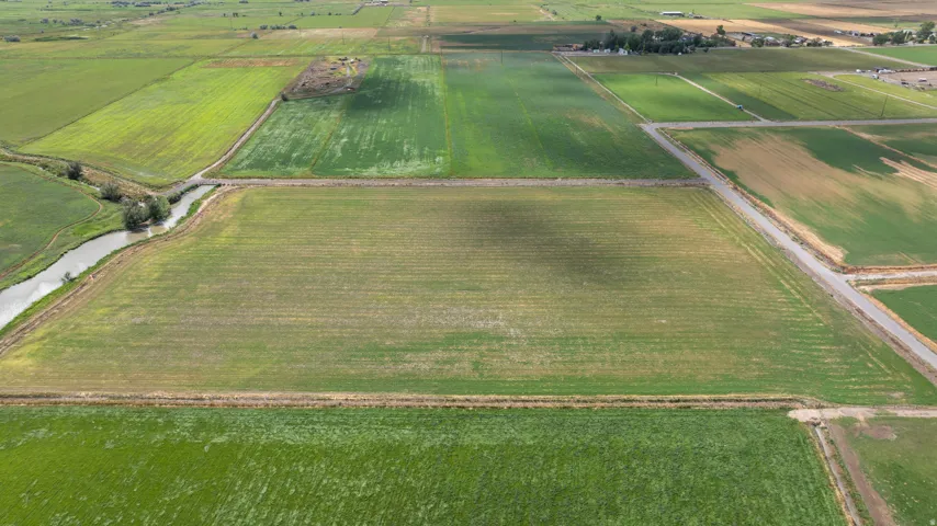 Expansive agricultural land featuring a waterway, multiple cultivated fields, and established perimeter roads