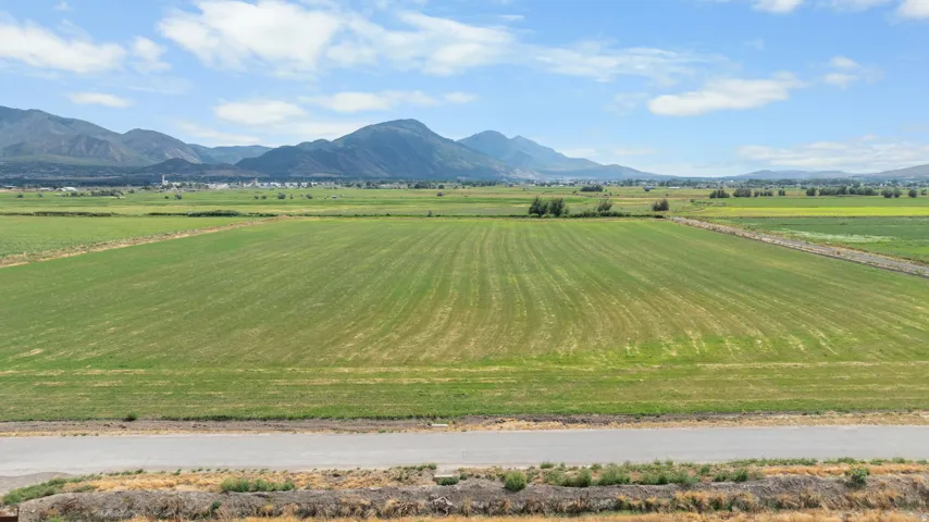 Expansive agricultural land featuring a paved road frontage and distant mountain ranges