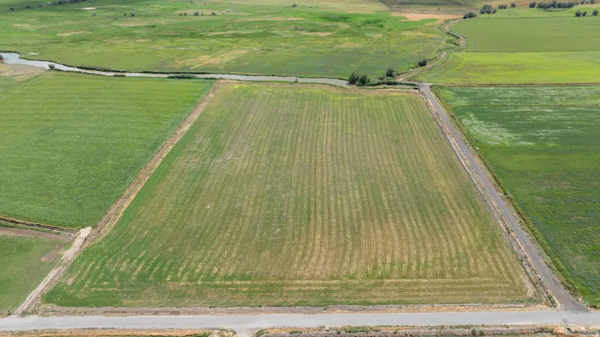 Expansive agricultural land featuring a visible irrigation canal and established access roads