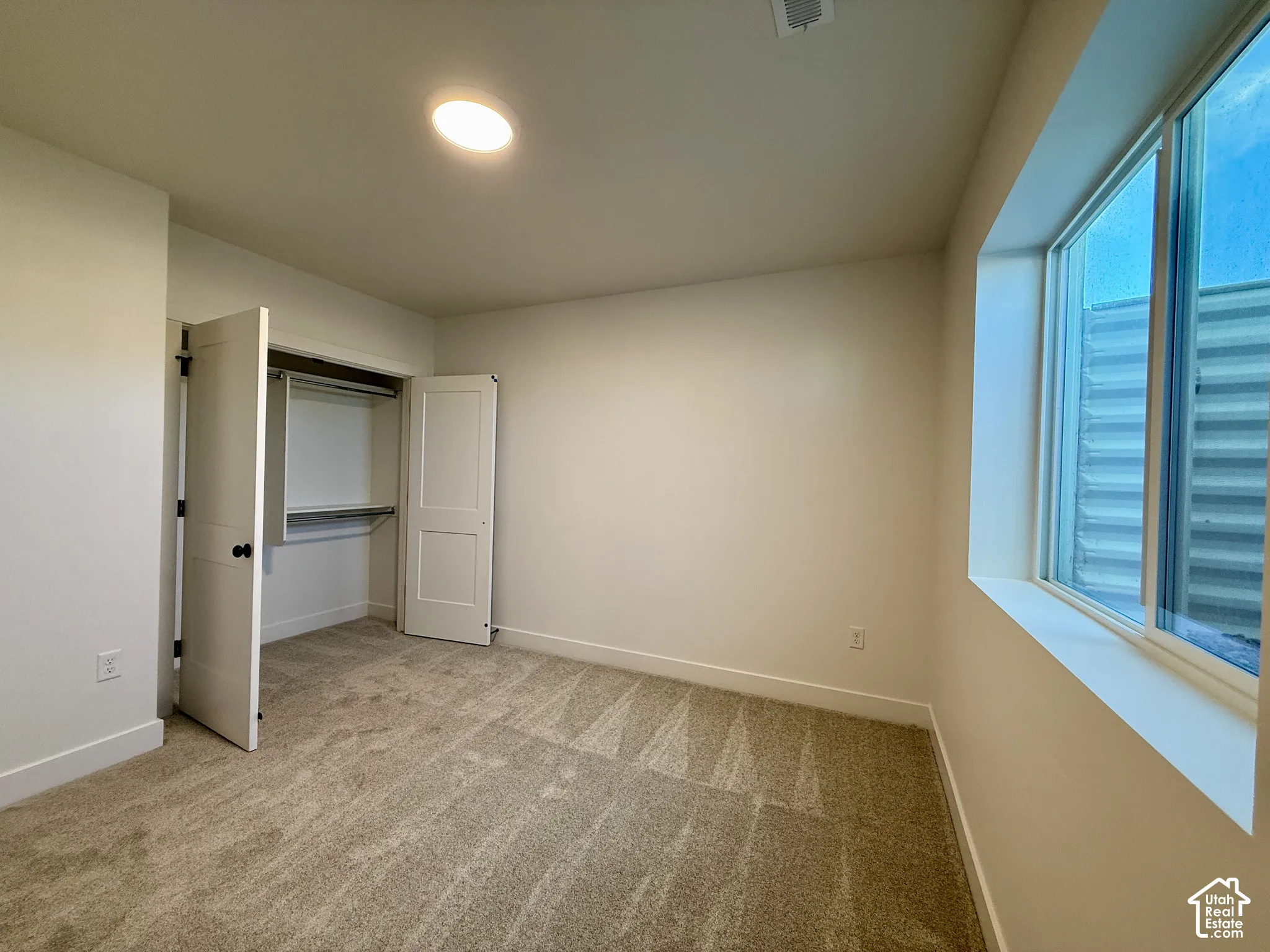 Neutral-toned carpeting, recessed ceiling lighting, and a closet featuring dual panel doors with built-in shelving