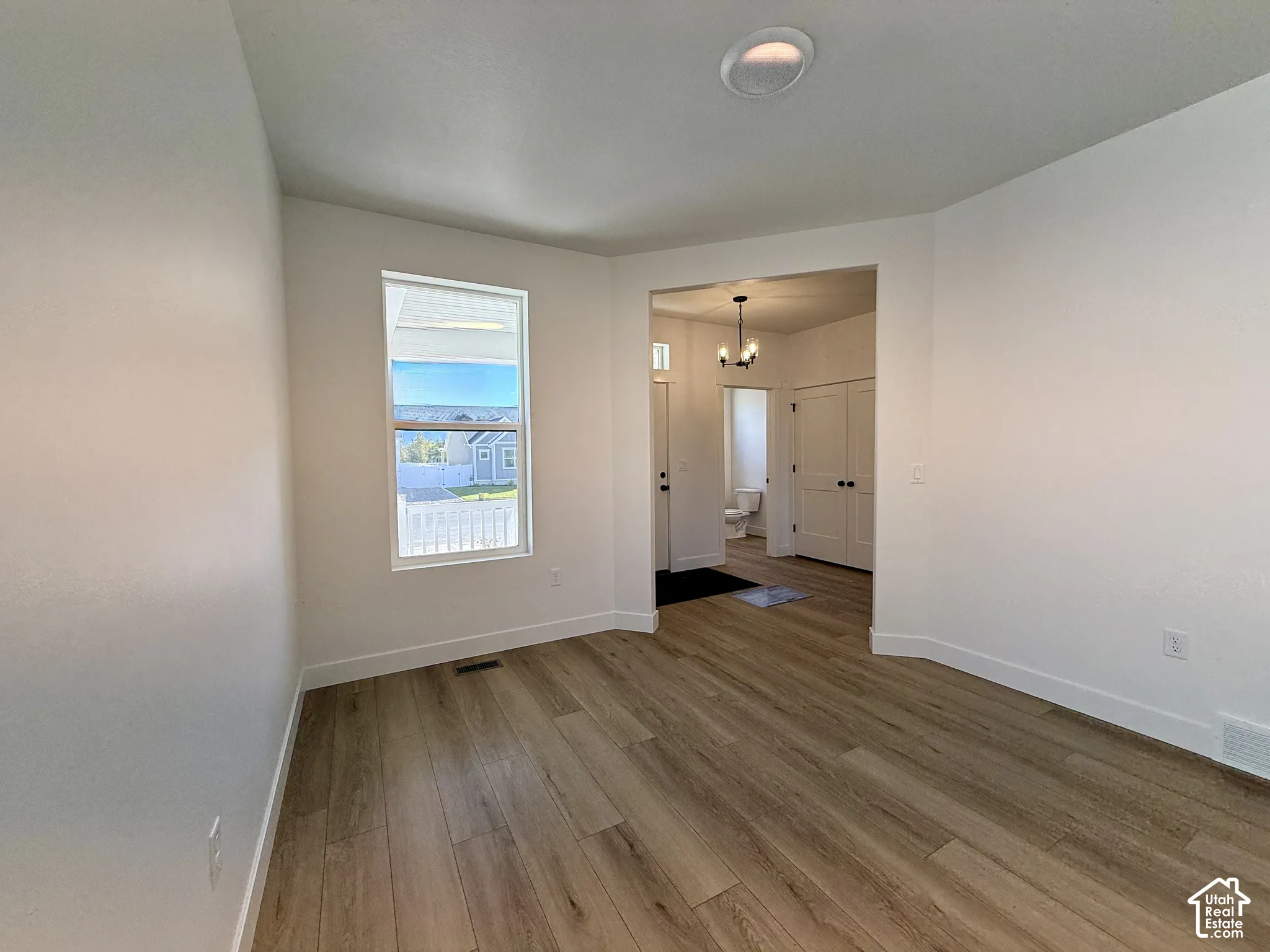 Wood-finish flooring, neutral walls, recessed lighting, and a multi-pane window