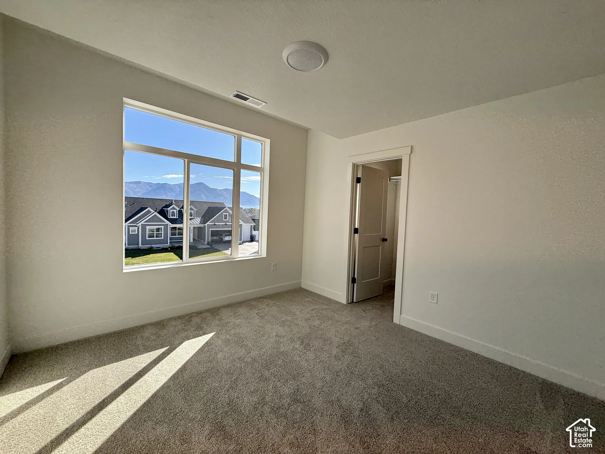 Room featuring large picture windows with mountain scenery, neutral carpeting, and a flush-mount ceiling light fixture