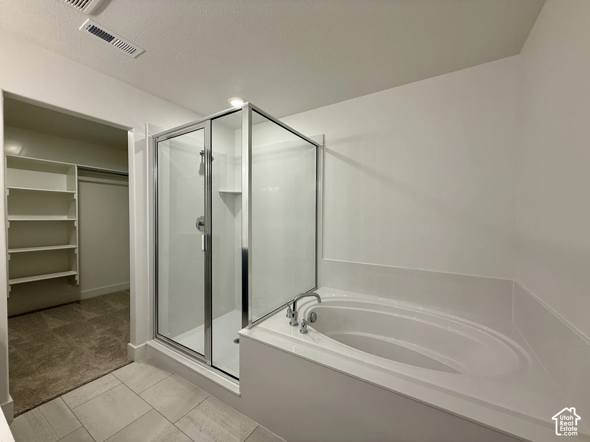 Glass-enclosed shower with a built-in ledge, deep soaking tub, and custom built-in shelving