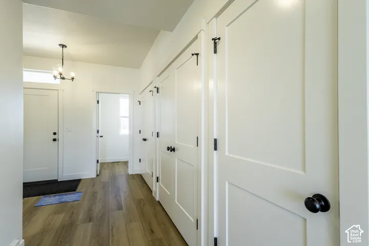 Recessed lighting, wood-finish flooring, white paneled doors with black hardware, and a modern chandelier